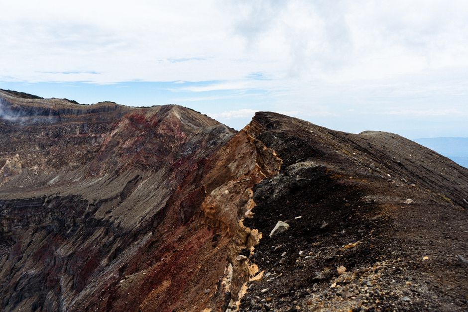 Dramatic view of a rugged volcanic landscape with rocky ridges under a cloudy sky.