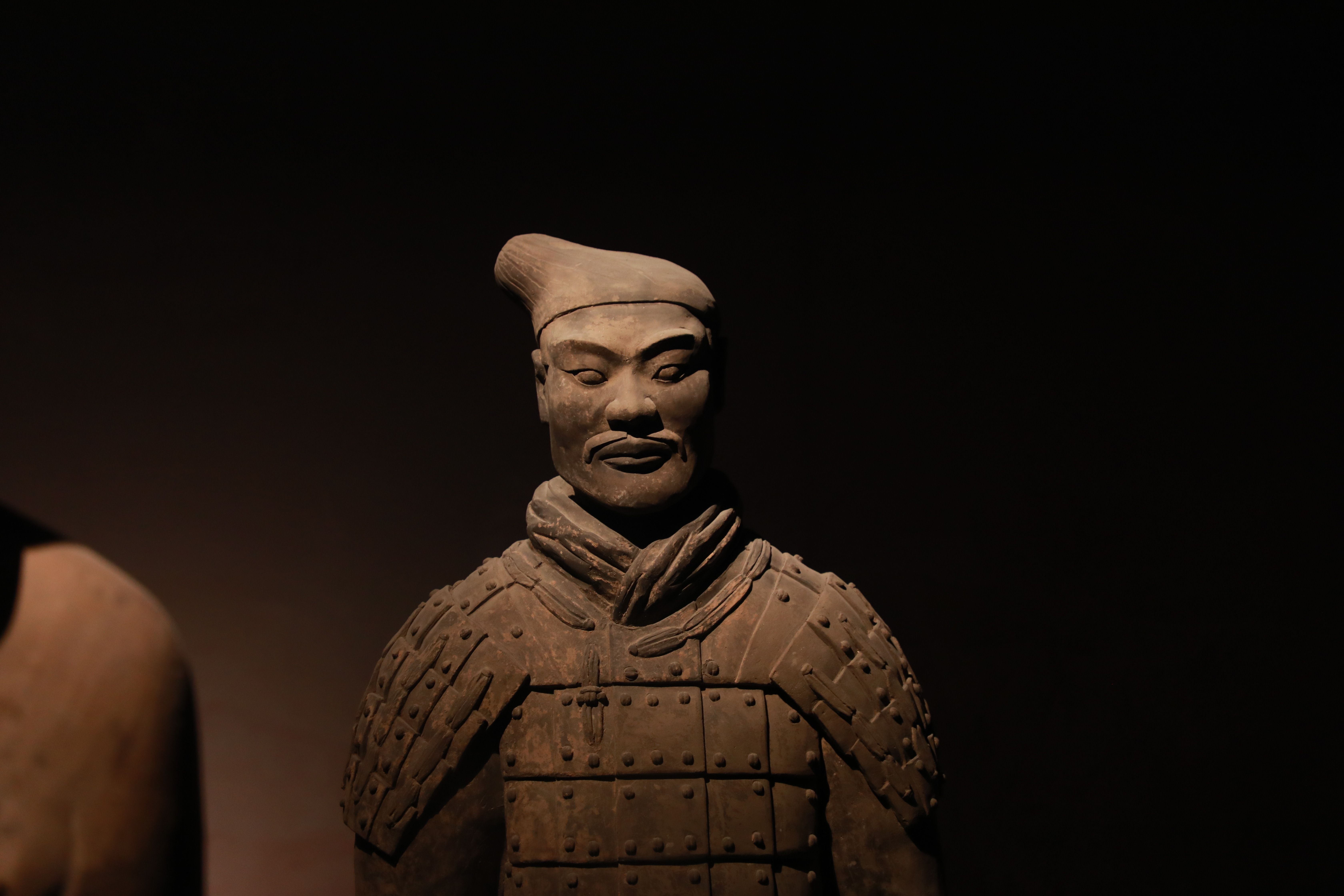 Close-up of a Terracotta Warrior statue with artistic lighting, capturing its detailed, historic features.