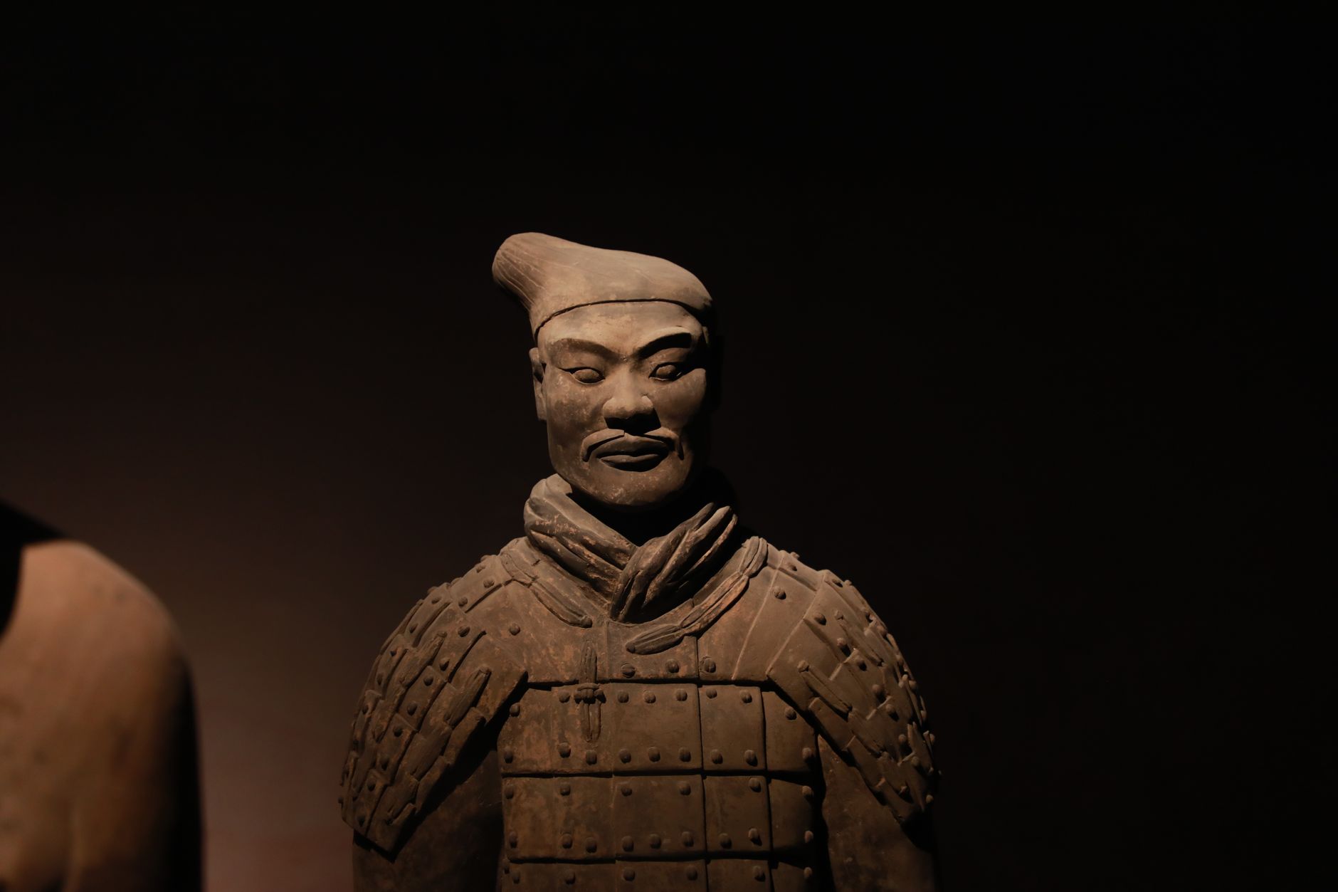 Close-up of a Terracotta Warrior statue with artistic lighting, capturing its detailed, historic features.