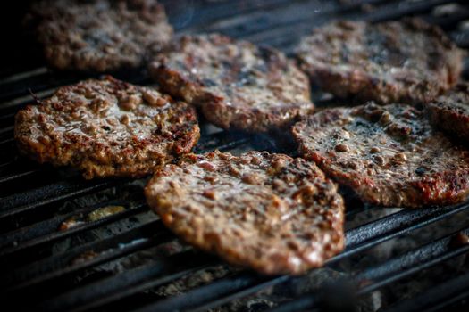 Juicy burger patties sizzling on a hot outdoor grill, perfect for a summer BBQ.