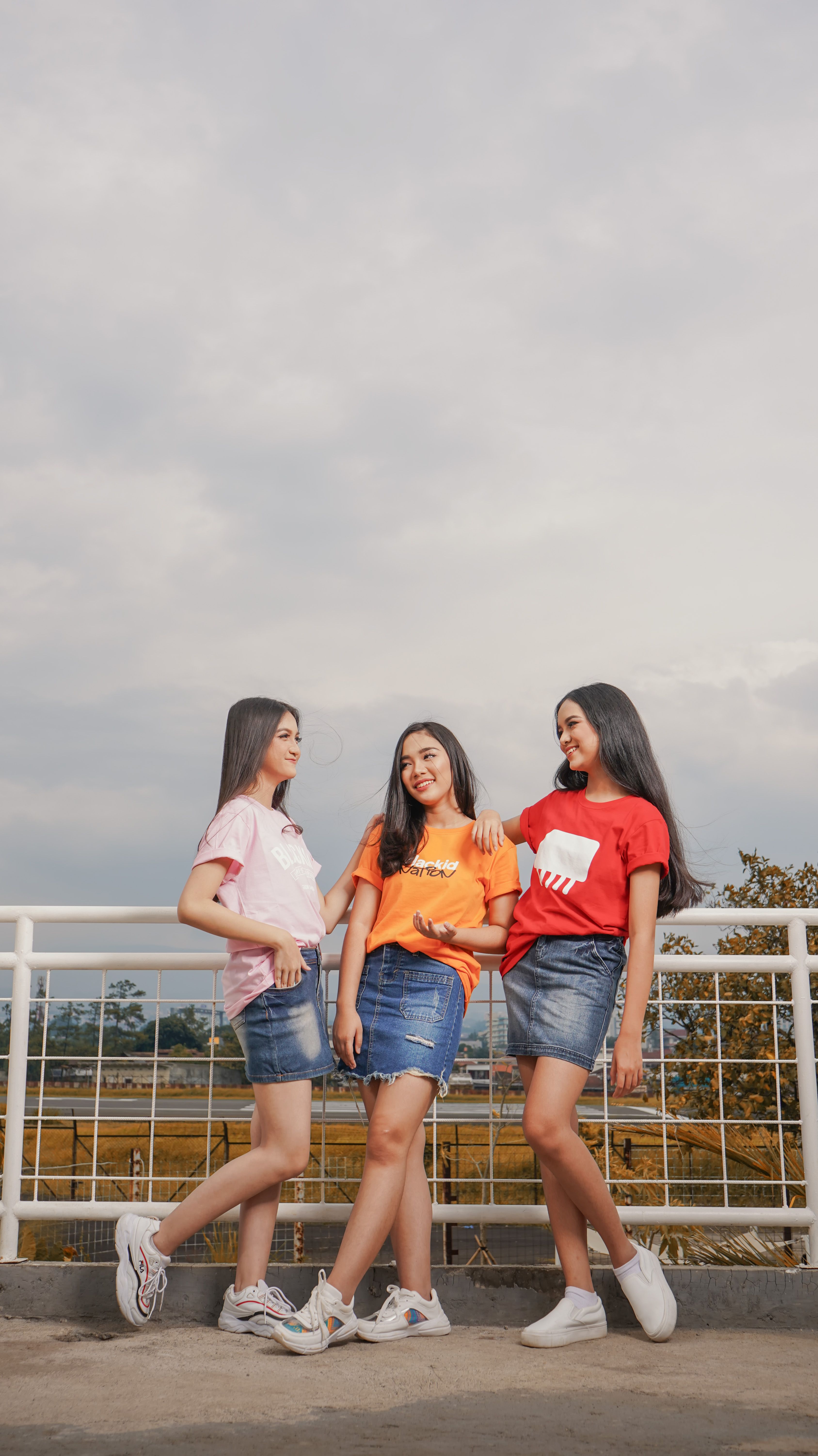 Group of three women in casual attire smiling and posing outdoors in Bandung, Indonesia.