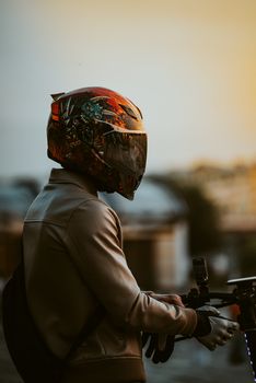 Motorcyclist wearing a colorful helmet at sunset, creating a dramatic silhouette.