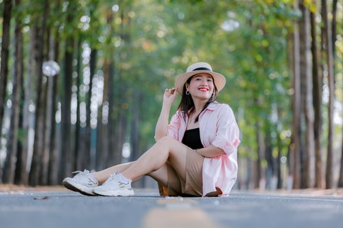 Free Woman enjoying nature sitting on a scenic road surrounded by trees. Stock Photo