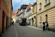 A picturesque European street scene with people walking and historical architecture under a clear sky.