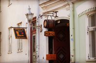 Rustic shop signs hanging on a historic building facade in Tallinn's Old Town.