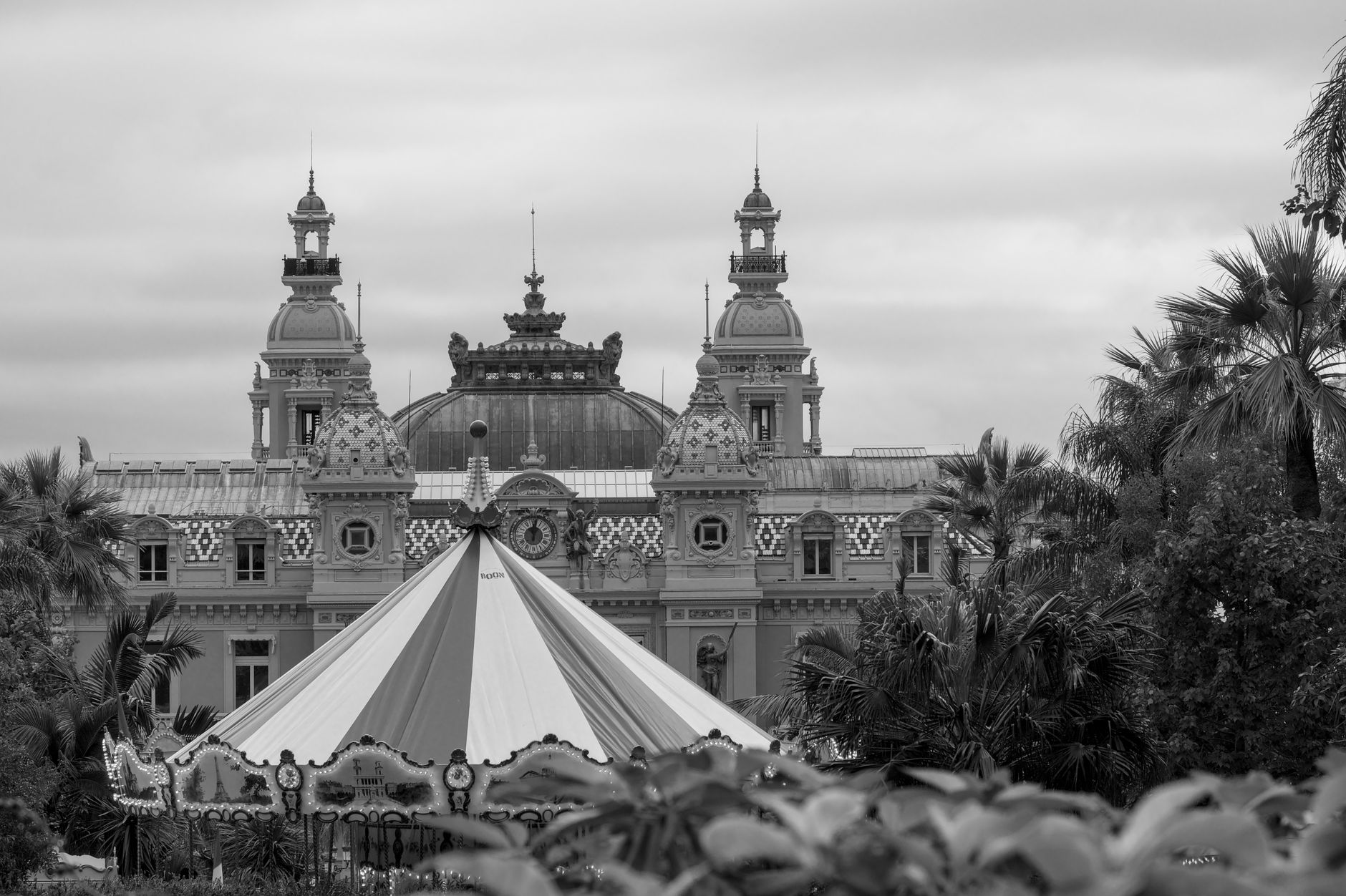Black and white view of Monte Carlo Casino with a carousel in foreground.