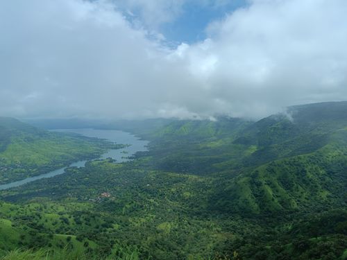 Free A breathtaking aerial view of green hills and a winding river under cloudy skies. Stock Photo