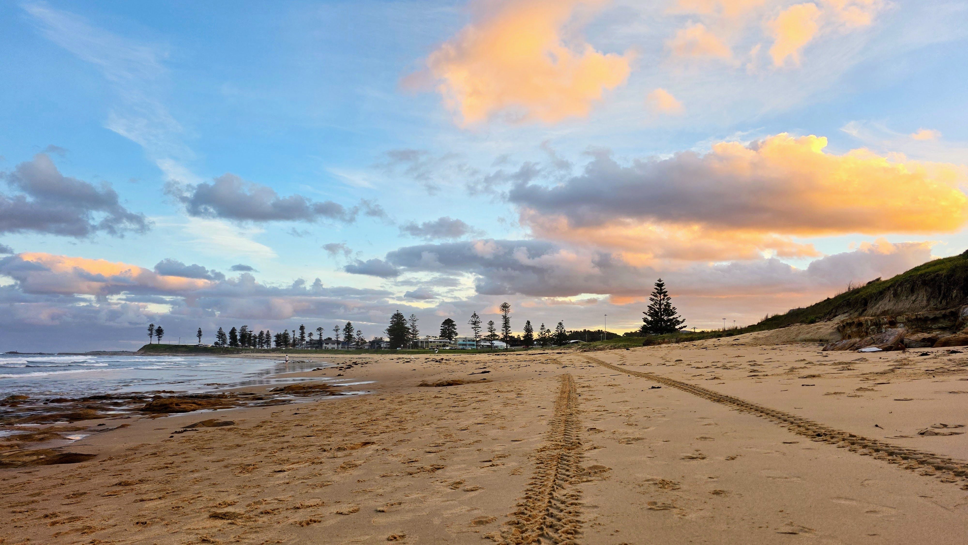 Tranquil evening on the sandy shores of Bulli Beach, NSW with vibrant sky and ocean views.