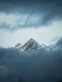 Captivating view of the snow-covered peaks emerging through dense clouds in Dharamshala, India.