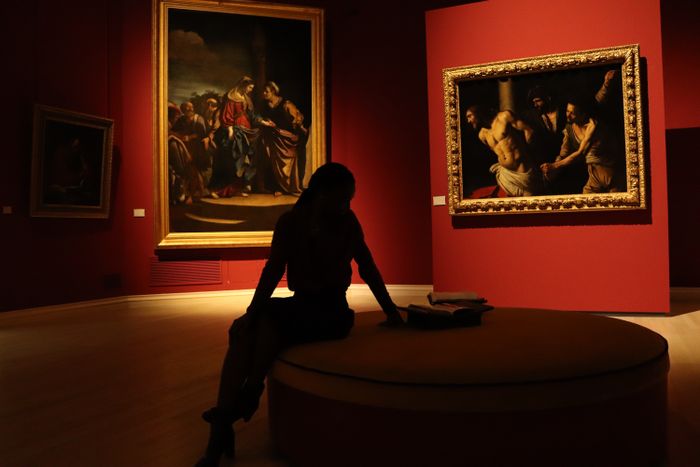 Visitor silhouetted in a dimly lit picture gallery — photo by Lo&iuml;c Manegarium on Pexels