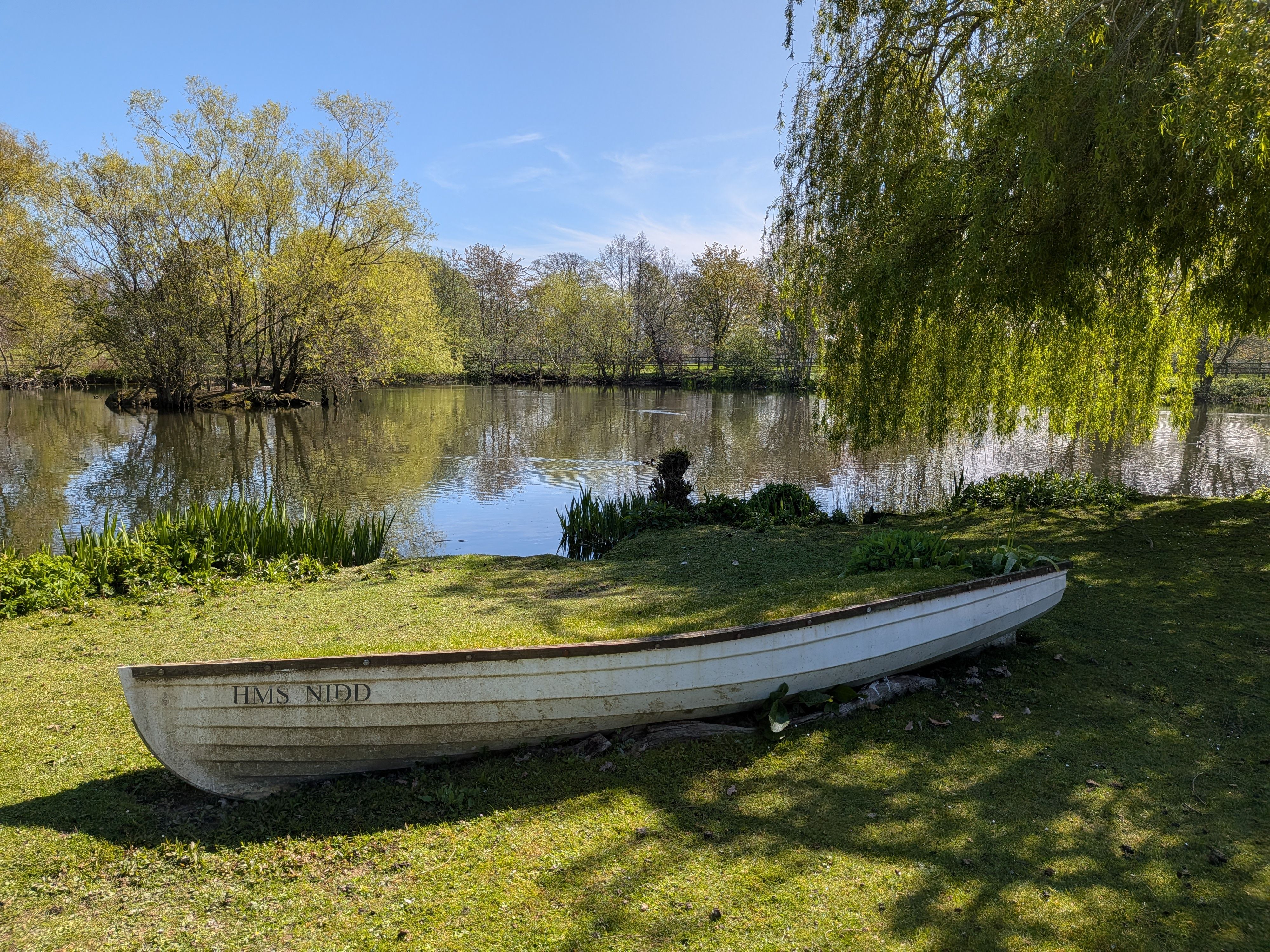 A serene scene of a boat beside a peaceful lake surrounded by trees in England.