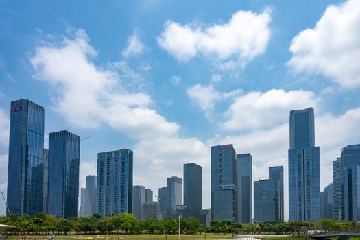 Skyscrapers in Shenzhen, China under a vibrant blue sky with fluffy clouds, showcasing urban architecture.