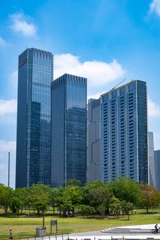 Skyscrapers in Shenzhen, China with lush greenery and blue sky.