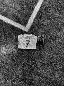 Black and white image of a soccer jersey and boots placed on a field's corner.