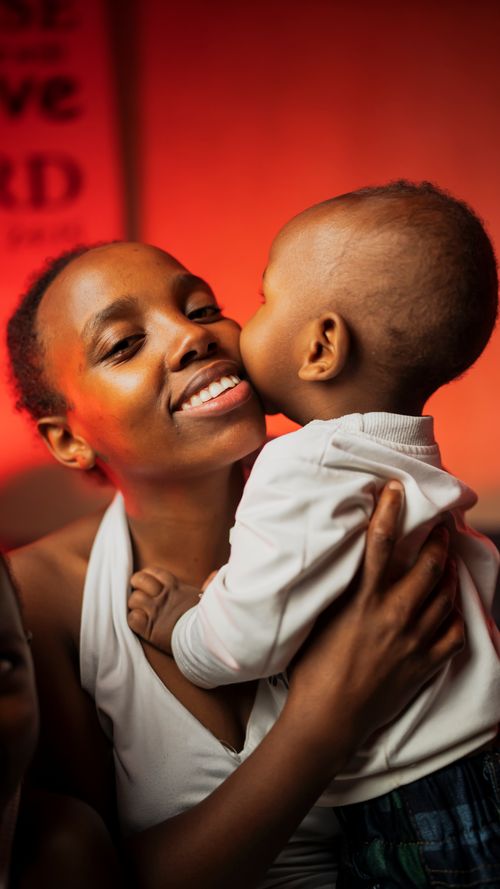 Free A loving African mother embraces her baby in a warm setting, highlighting familial love. Stock Photo