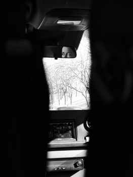 Black and white photo of a person in a rearview mirror capturing a street view in İstanbul.