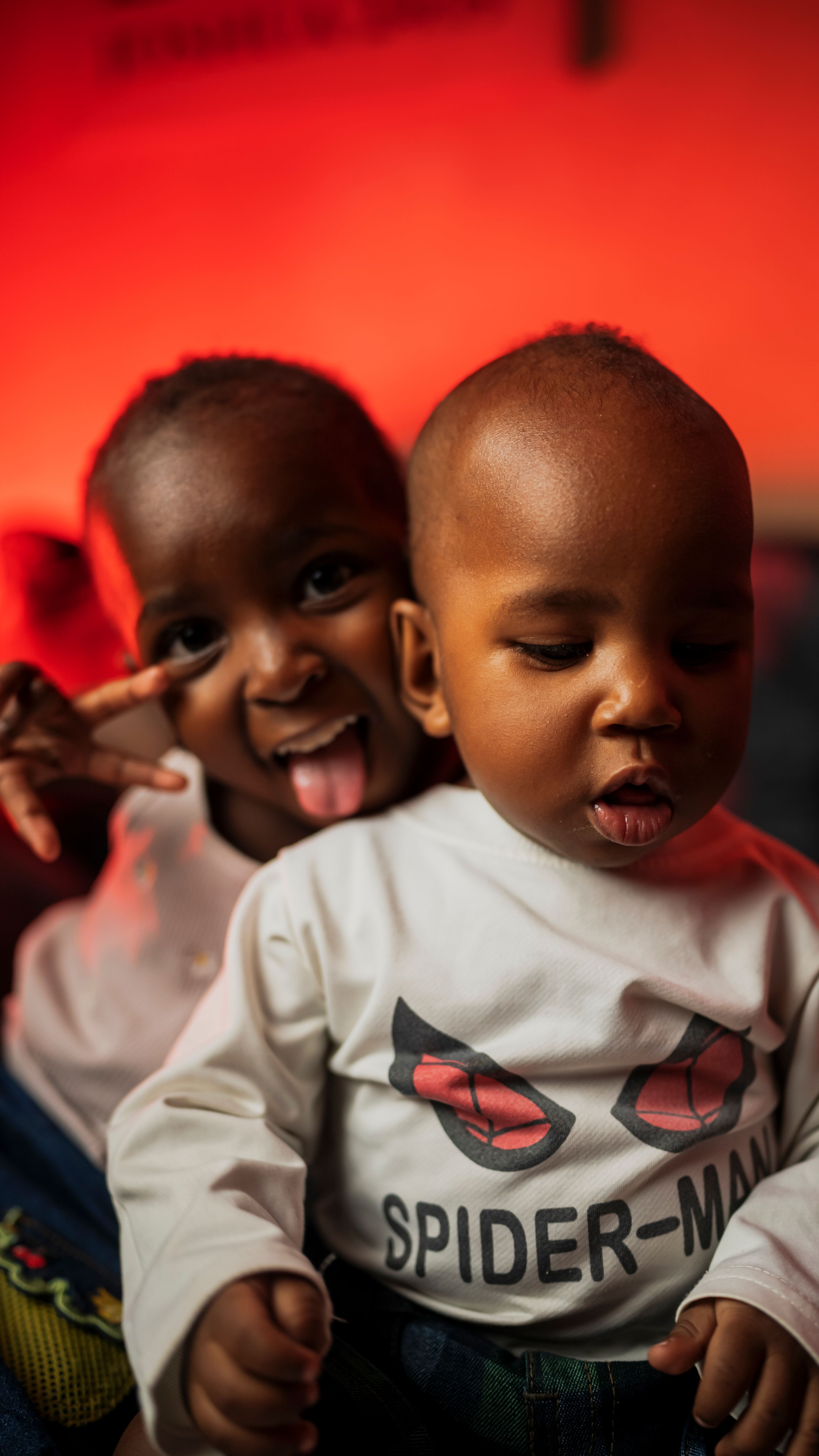 Two siblings express joy and playfulness indoors in Nairobi, Kenya.