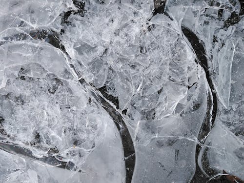 Top view of fragile ice broken into small thin transparent pieces in frosty weather