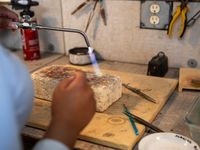 Hands working a blowtorch over a small piece — photo by Mazin Omron on Pexels