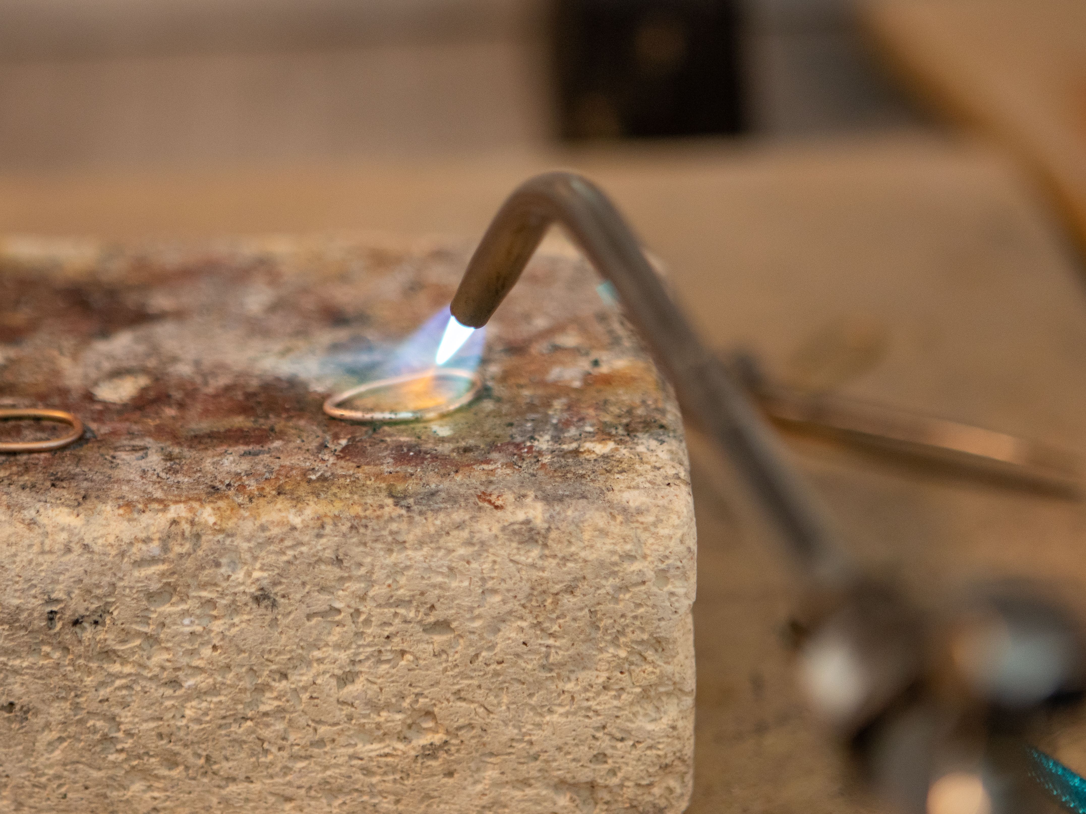 A detailed view of a metal welding process with a flame torch focused on a metal piece.