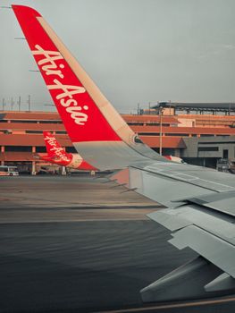 AirAsia aircraft wing view at Thailand's Samut Prakan Airport.