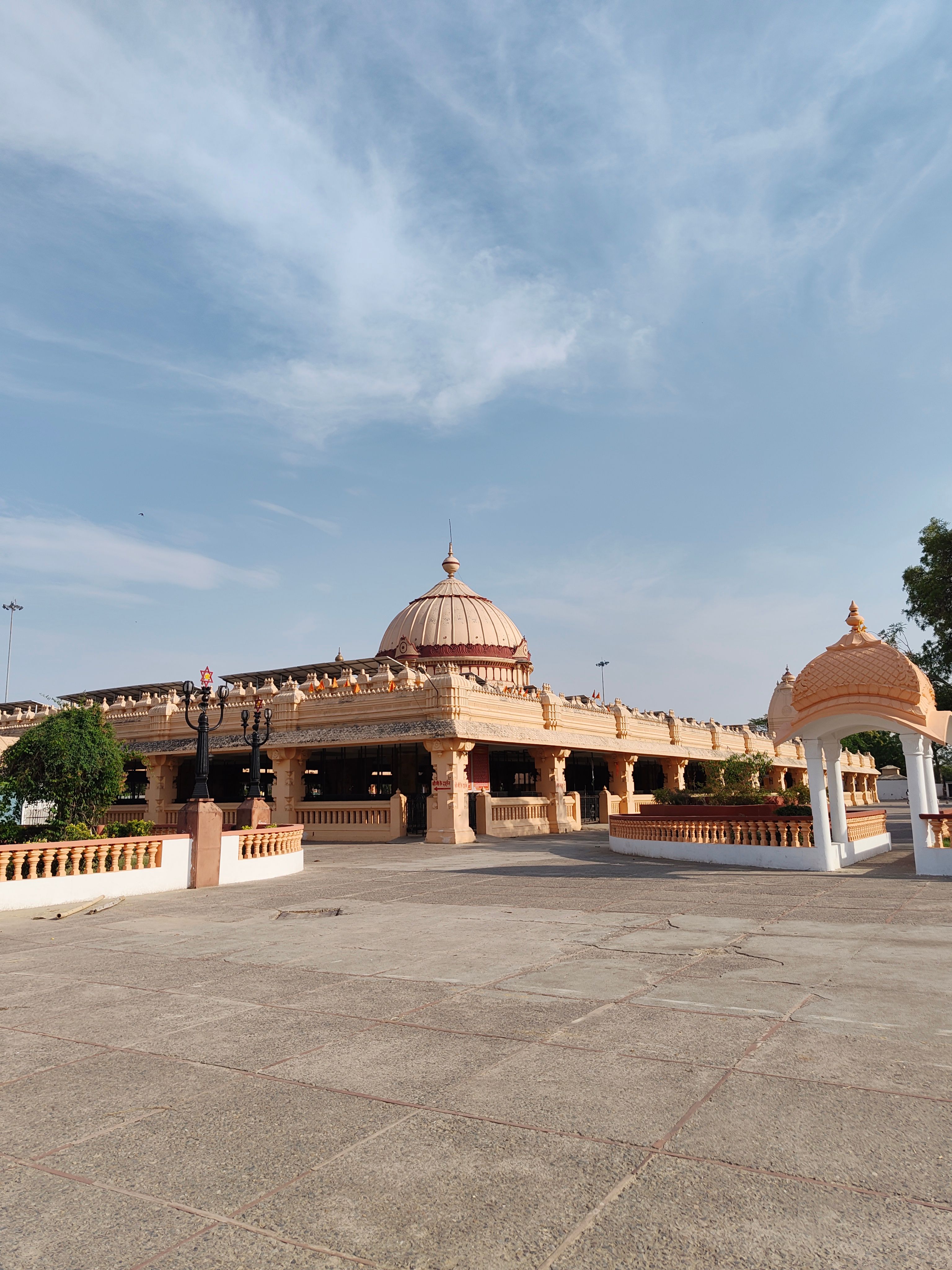 A beautiful Hindu temple featuring a grand dome and archways under a clear sky.