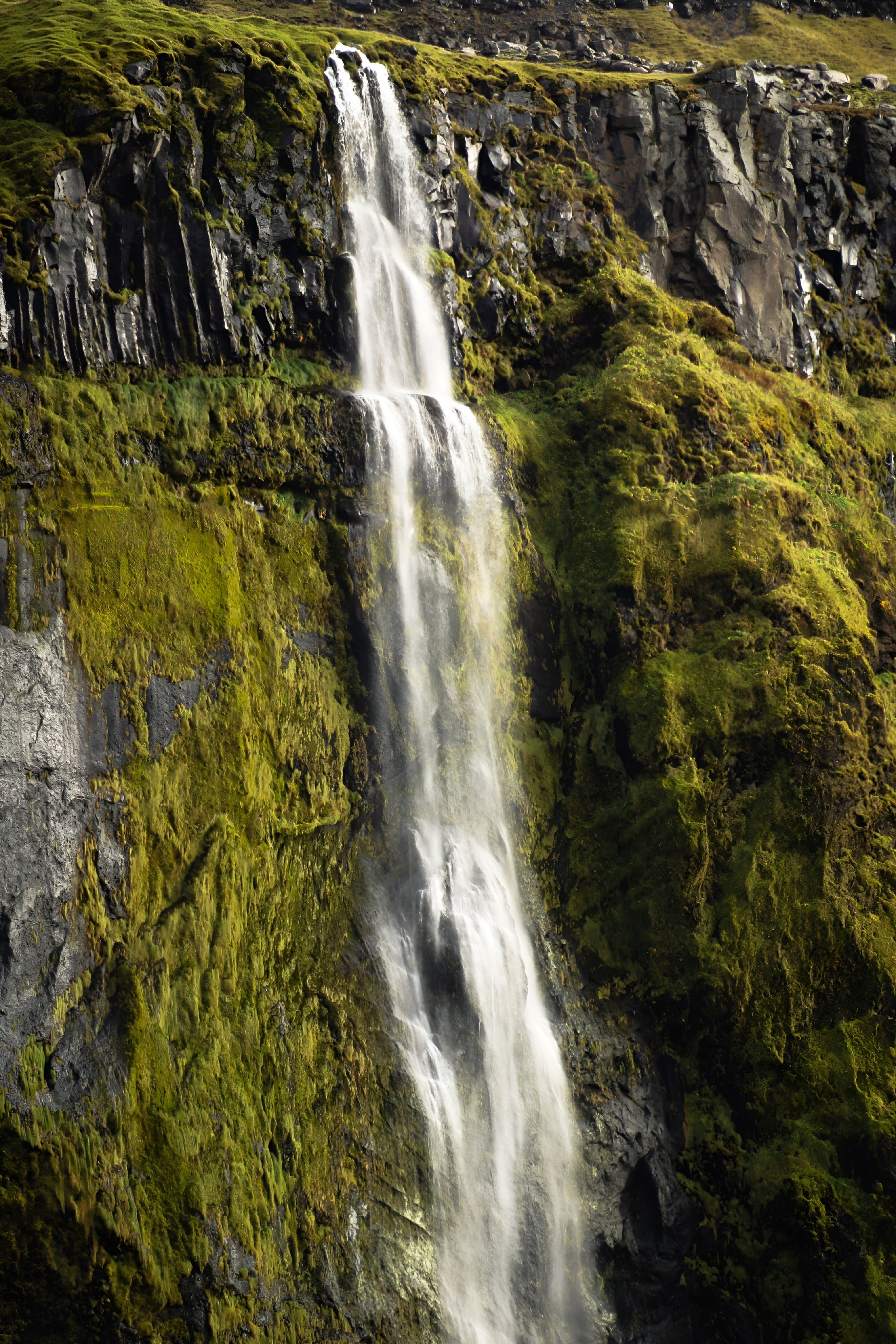 A breathtaking waterfall cascades down lush, green cliffs creating a serene natural spectacle.