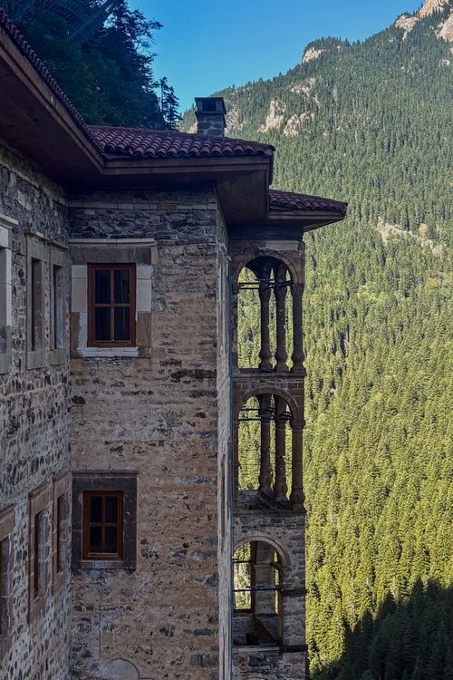 Free Stone monastery facade with intricate arches set against lush green mountains. Stock Photo