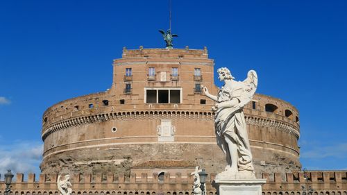 Free A breathtaking view of Castel Sant'Angelo and angel statue under clear blue skies in Rome. Stock Photo