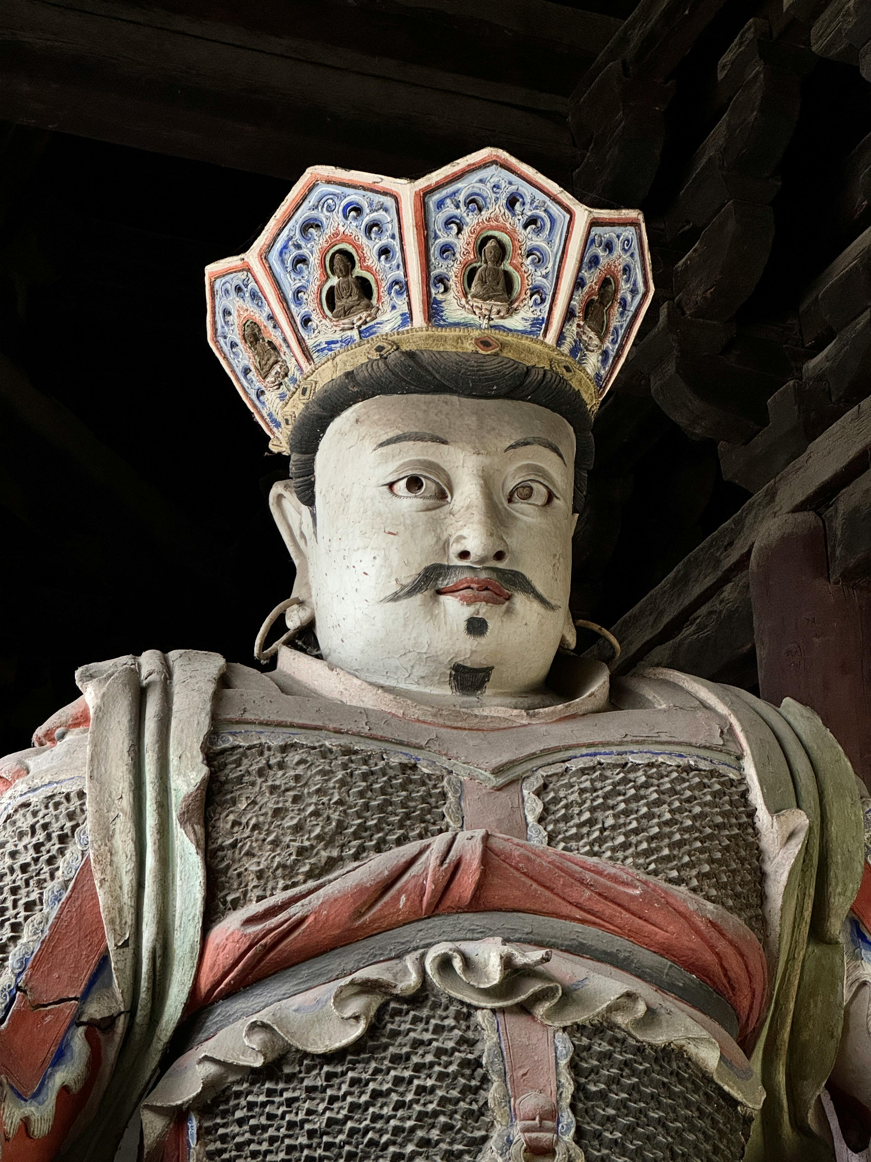 Close-up of a detailed ancient warrior statue in a historic temple setting.