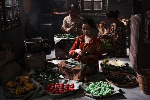 Women preparing traditional Indonesian snacks in a rustic kitchen, showcasing cultural culinary practices.