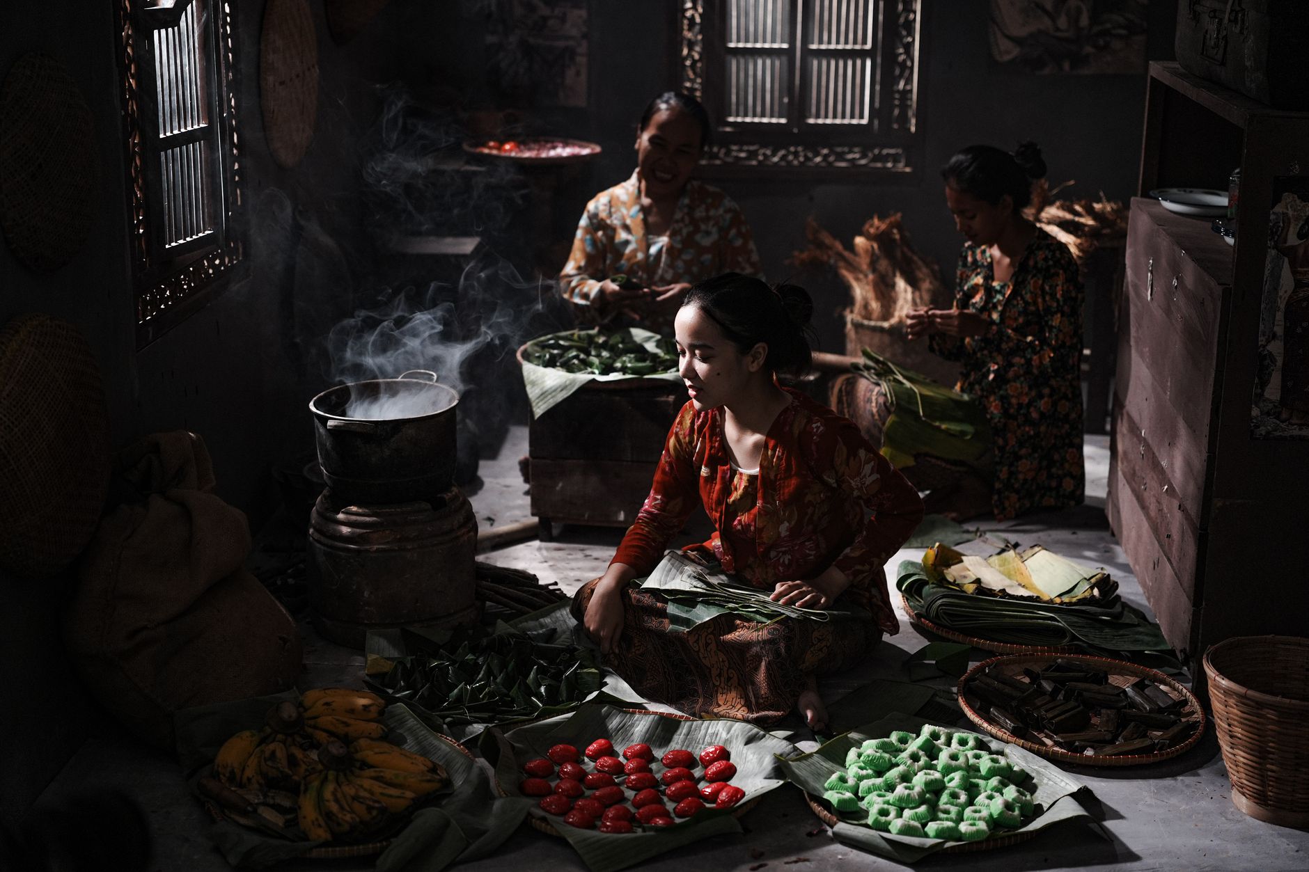 Authentic indoor scene of women preparing food with traditional Indonesian ingredients.