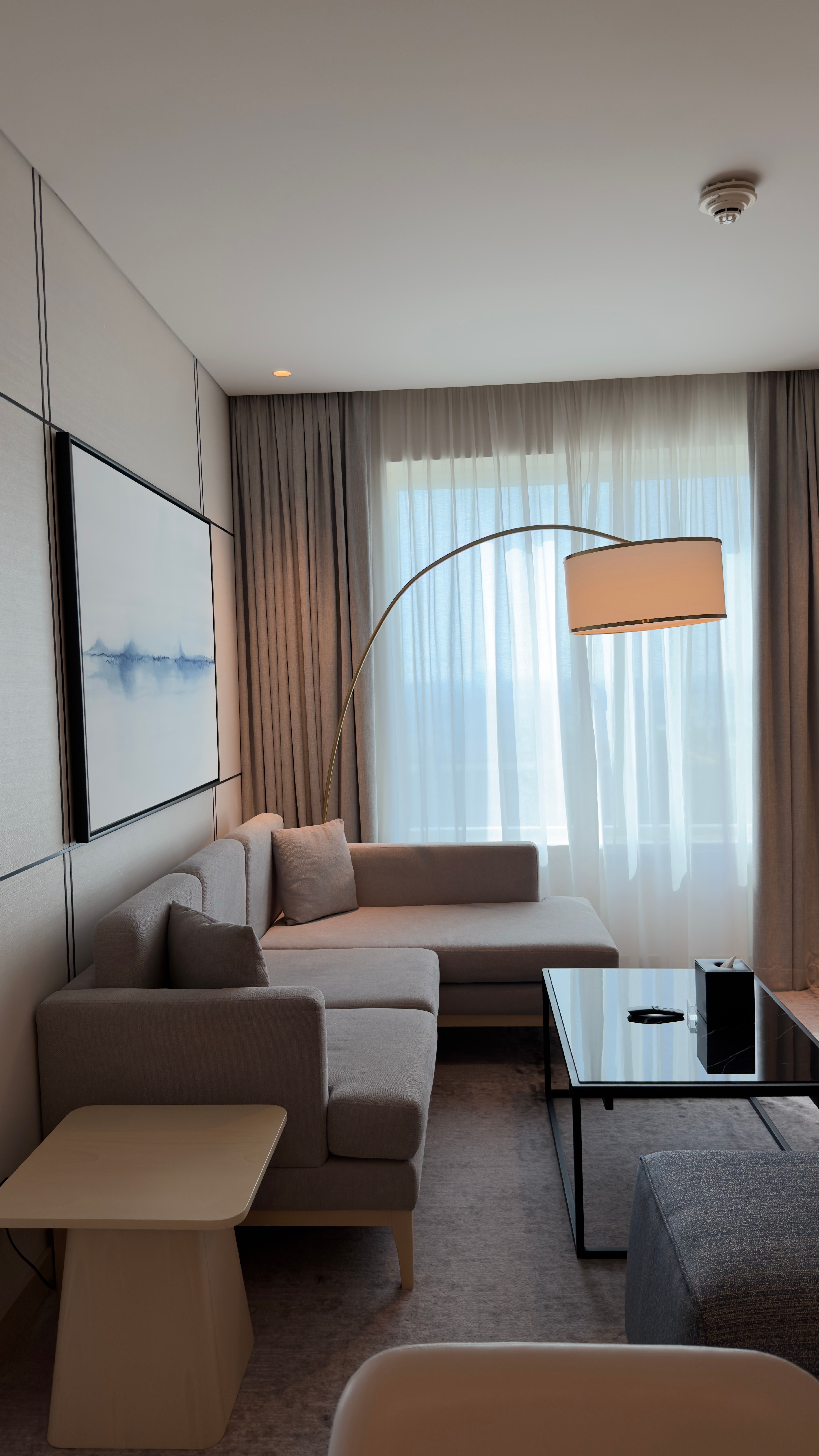 Bright modern living room with cozy couch, stylish lamp, and abstract art in a minimalist style.