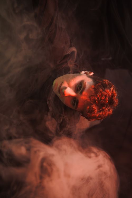 Free Artistic portrait of a young adult in smoke with dramatic lighting. Stock Photo