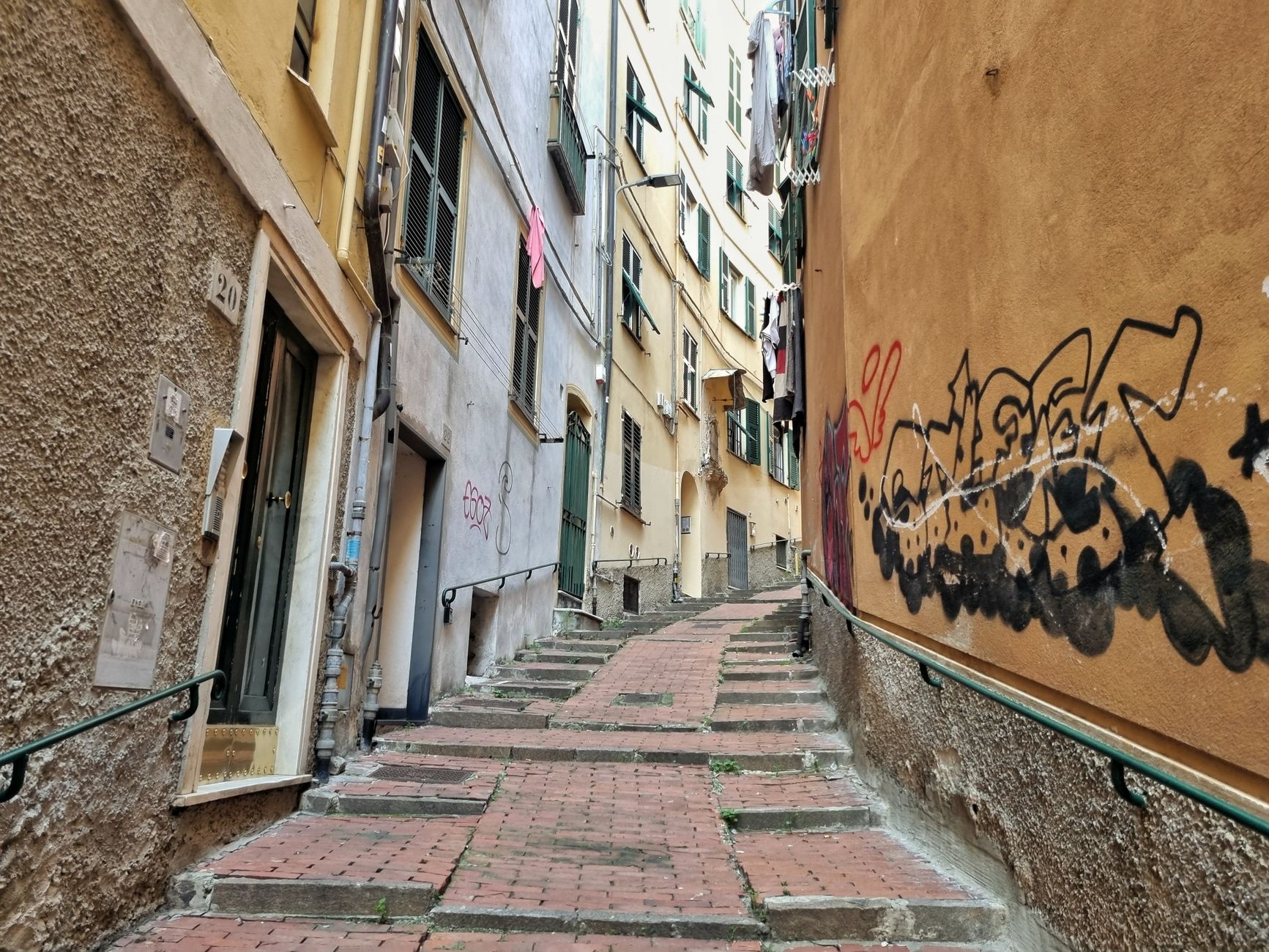 Discover the rustic charm of a graffiti-adorned alley in Liguria, Italy.