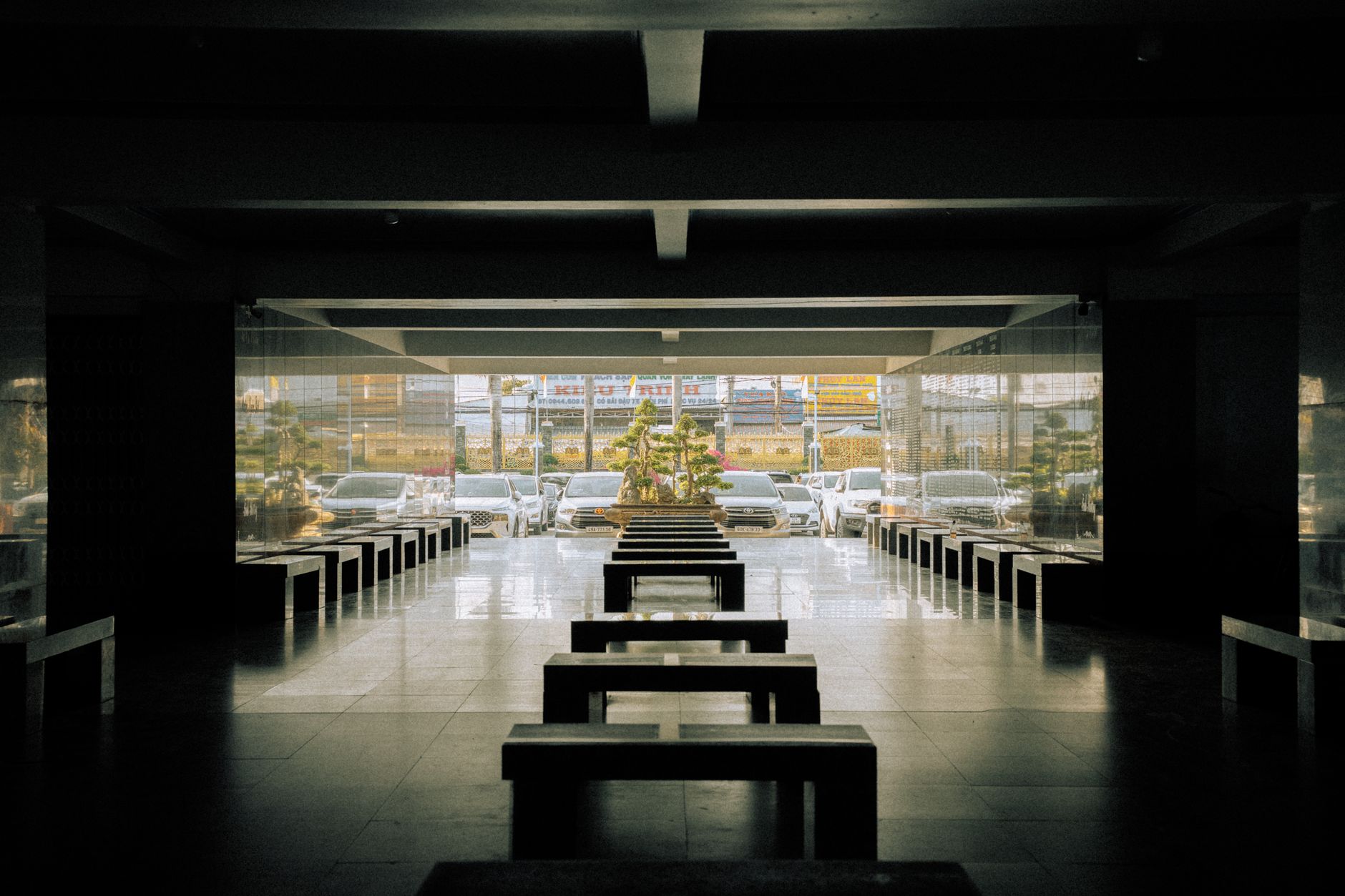 A modern interior view highlighting symmetrical benches leading to a parking area in Phong Thạnh, Cà Mau.