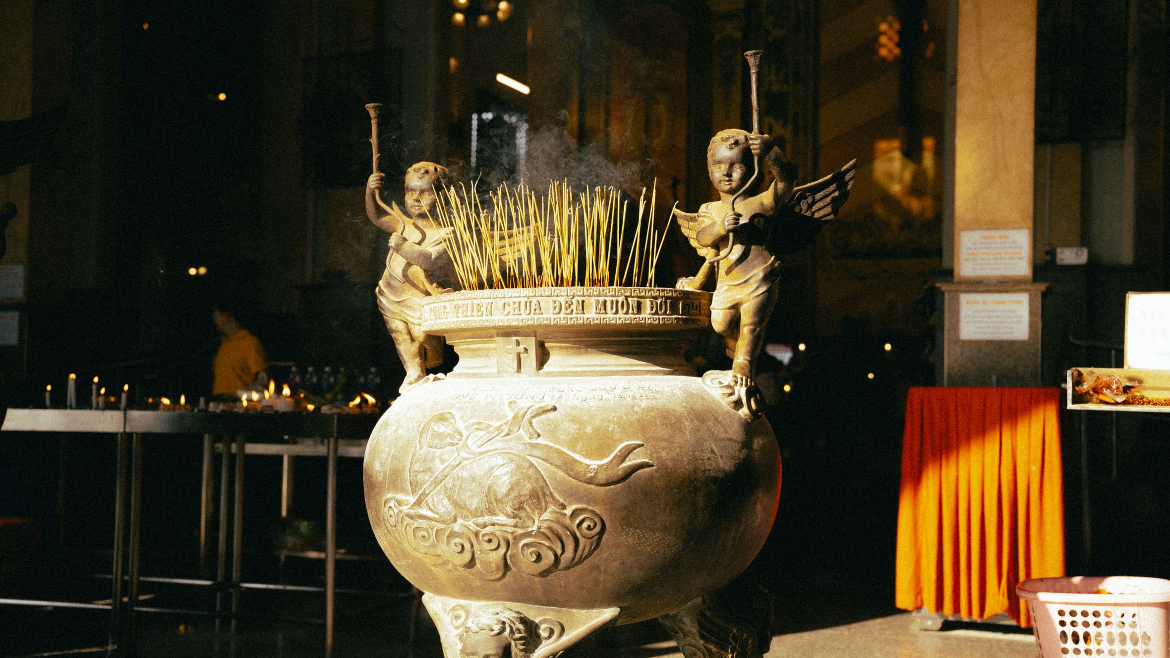 Intricately carved incense burner with smoke in a temple in Cà Mau, Vietnam.