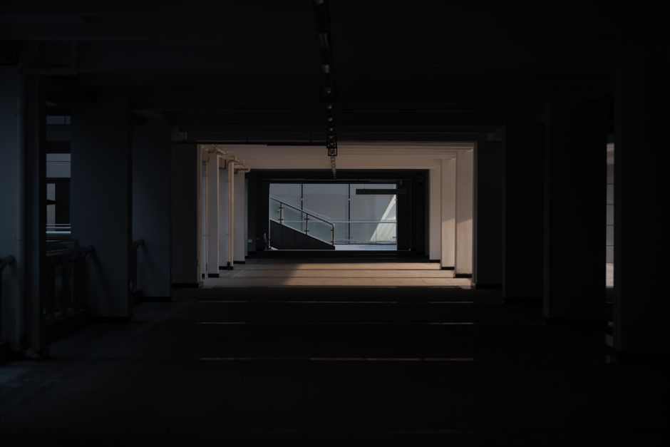 薄暗い照明に照らされた都市の建築回廊を捉えた、物憂げな眺め。ドラマチックで神秘的な雰囲気を醸し出している。