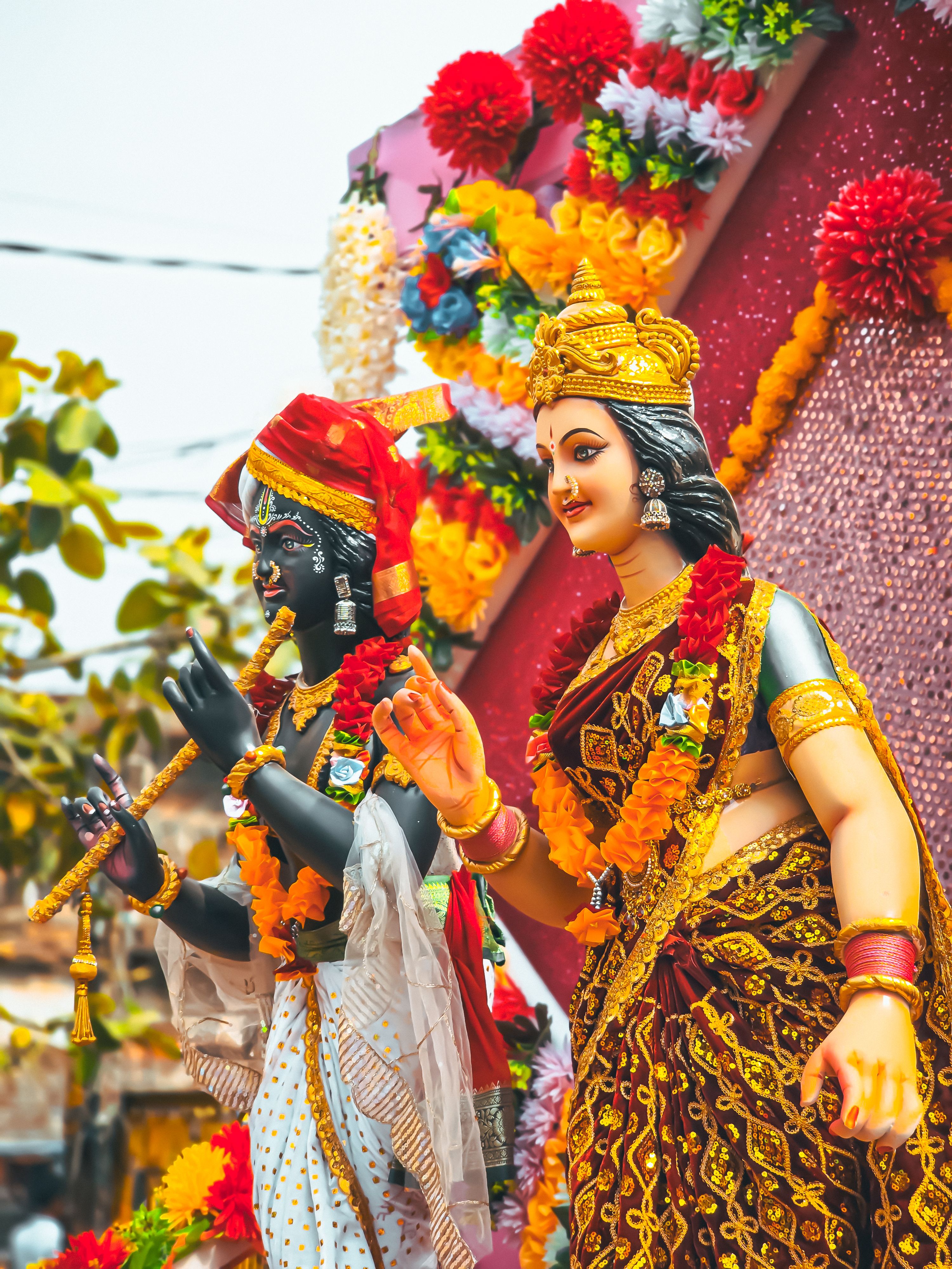 Colorful statues of Hindu deities adorned with flowers during a festive celebration.