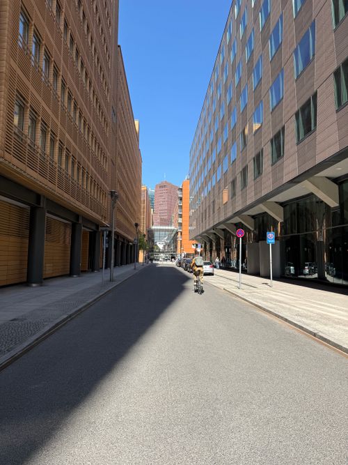 Free A quiet city street flanked by modern skyscrapers under a clear blue sky. Stock Photo
