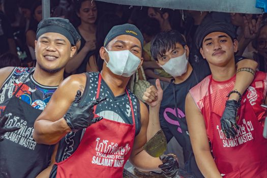 Street food vendors smile and pose during a vibrant festival in Manila, Philippines.