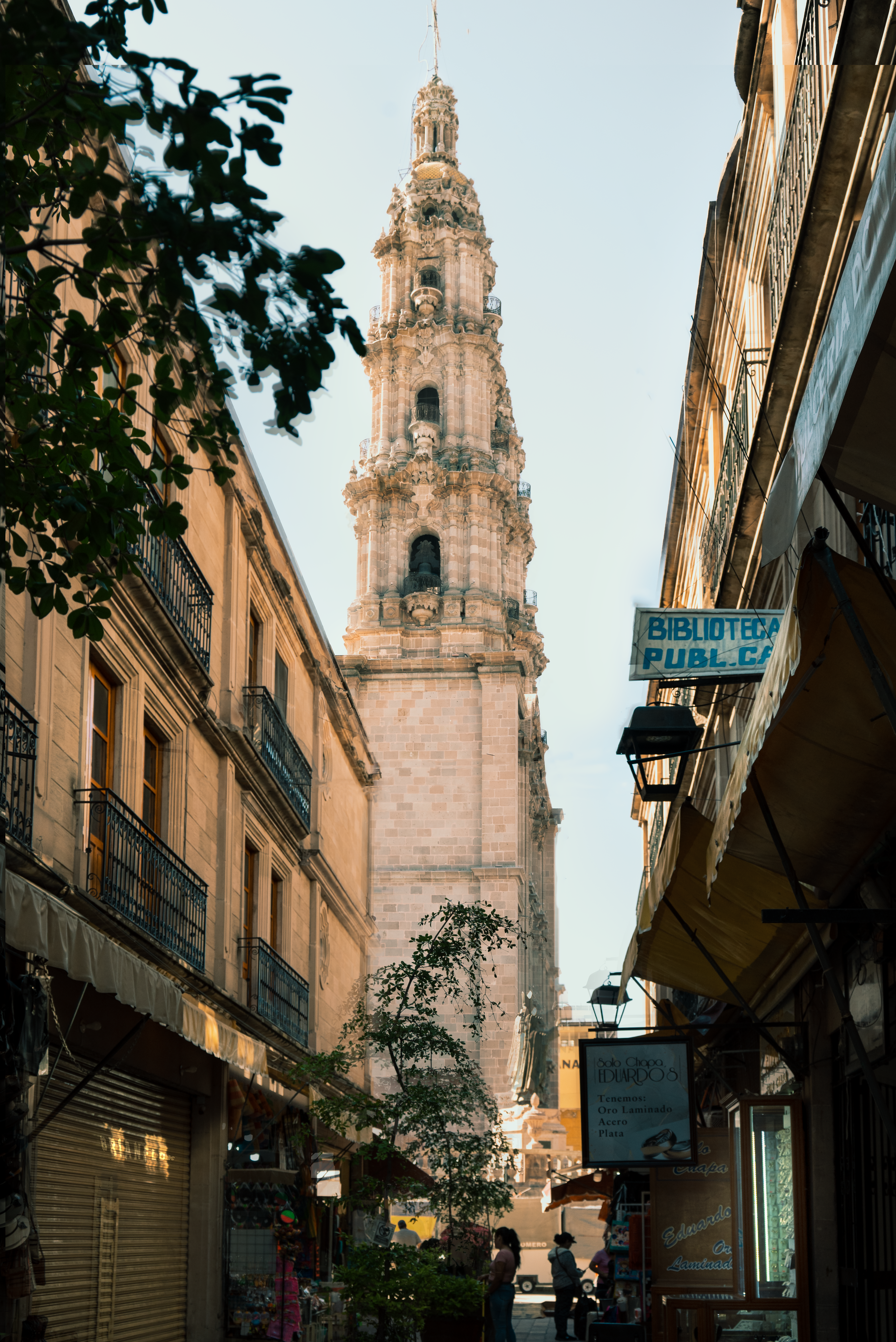 gratis Prachtig uitzicht op een historische klokkentoren, gezien door een schilderachtig steegje met winkeltjes. Stockfoto