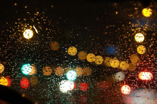 Defocused city lights through a rain-soaked window in Kyiv at night, creating a bokeh effect.