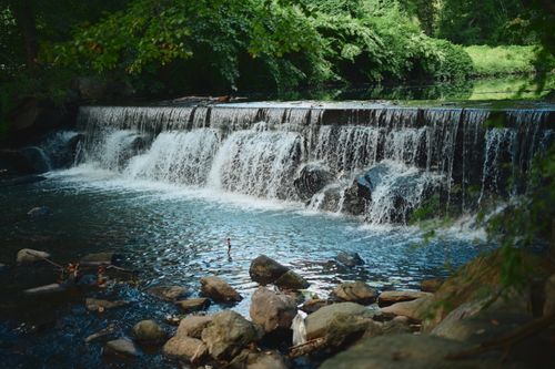 Free Serene waterfall cascading over rocks in a lush green forest setting, perfect for nature themes. Stock Photo