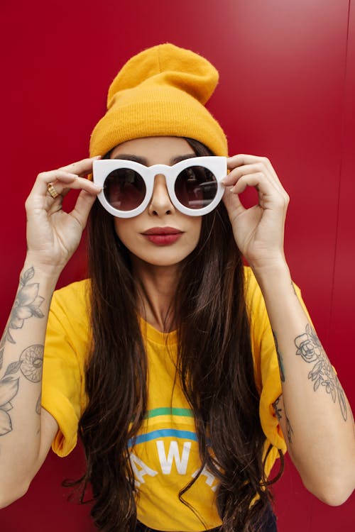 Женщина в желтой вязаной шапке и белых солнцезащитных очках в оправе