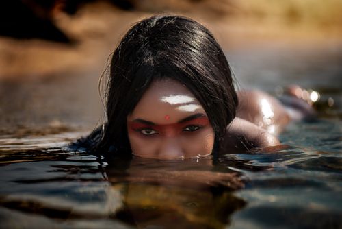Free Captivating image of an enigmatic woman with traditional markings emerging from the water. Stock Photo