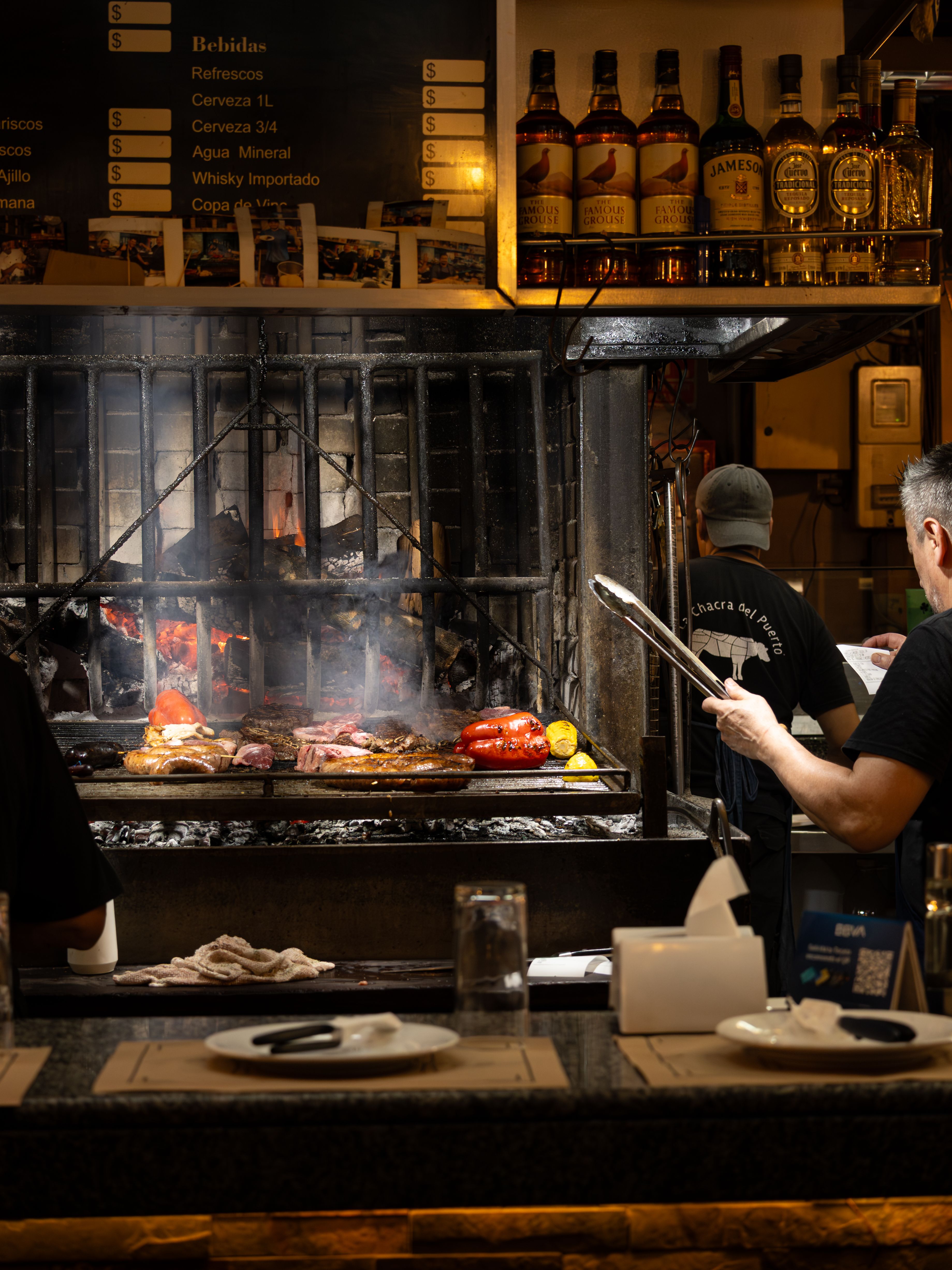 Fotomural Un chef prepara hábilmente asado tradicional en una parrilla en un restaurante de Montevideo.