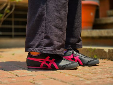Close-up of stylish sneakers on a sunny brick pathway in Bengaluru, India.