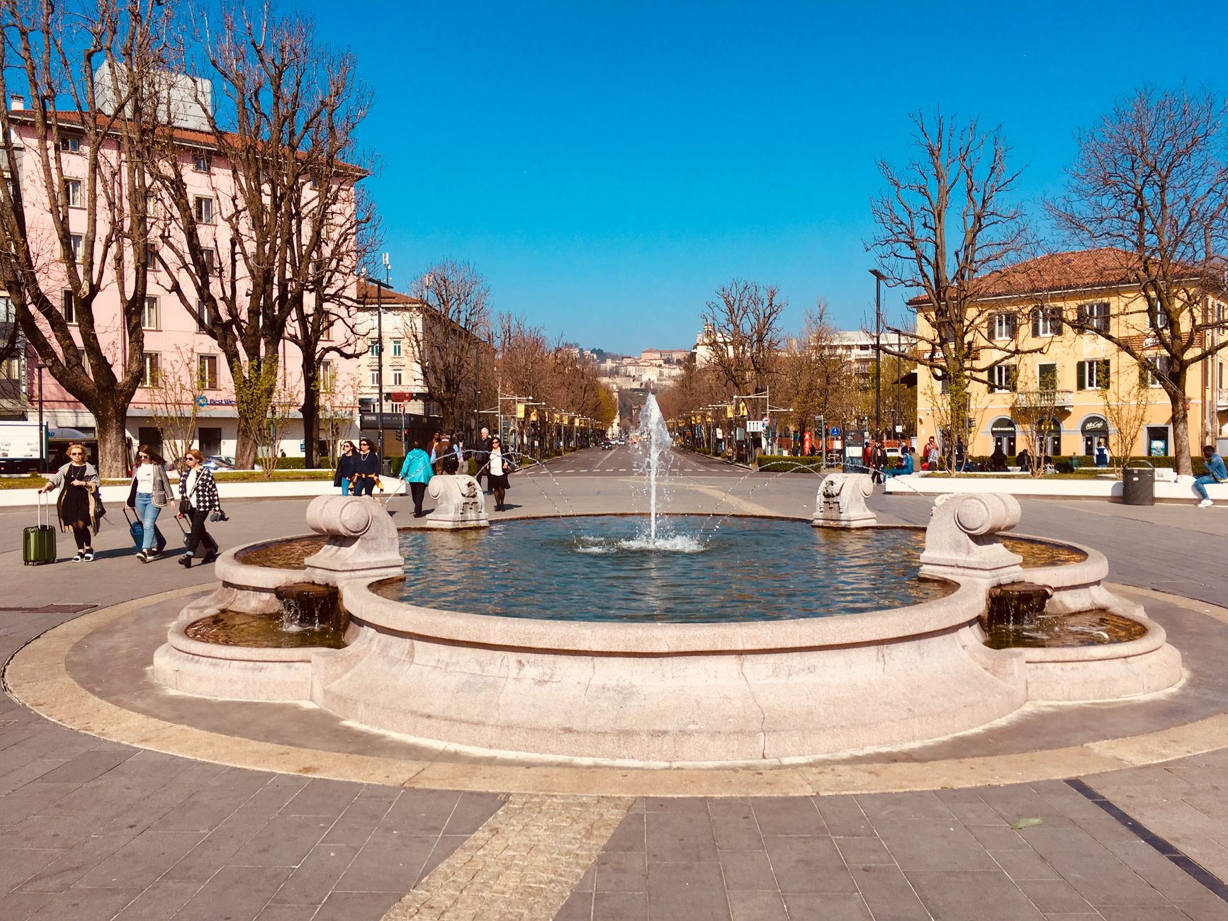 Sunny day scene with a fountain on Viale Papa Giovanni XXIII in Bergamo, Italy, showcasing urban arc