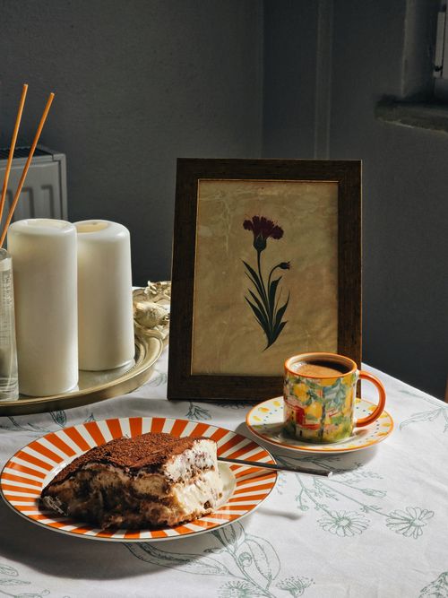 Free A warm indoor scene featuring tiramisu, coffee, candles, and floral decor. Stock Photo